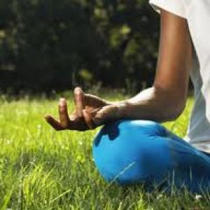 A photo of a person meditating in the grass.