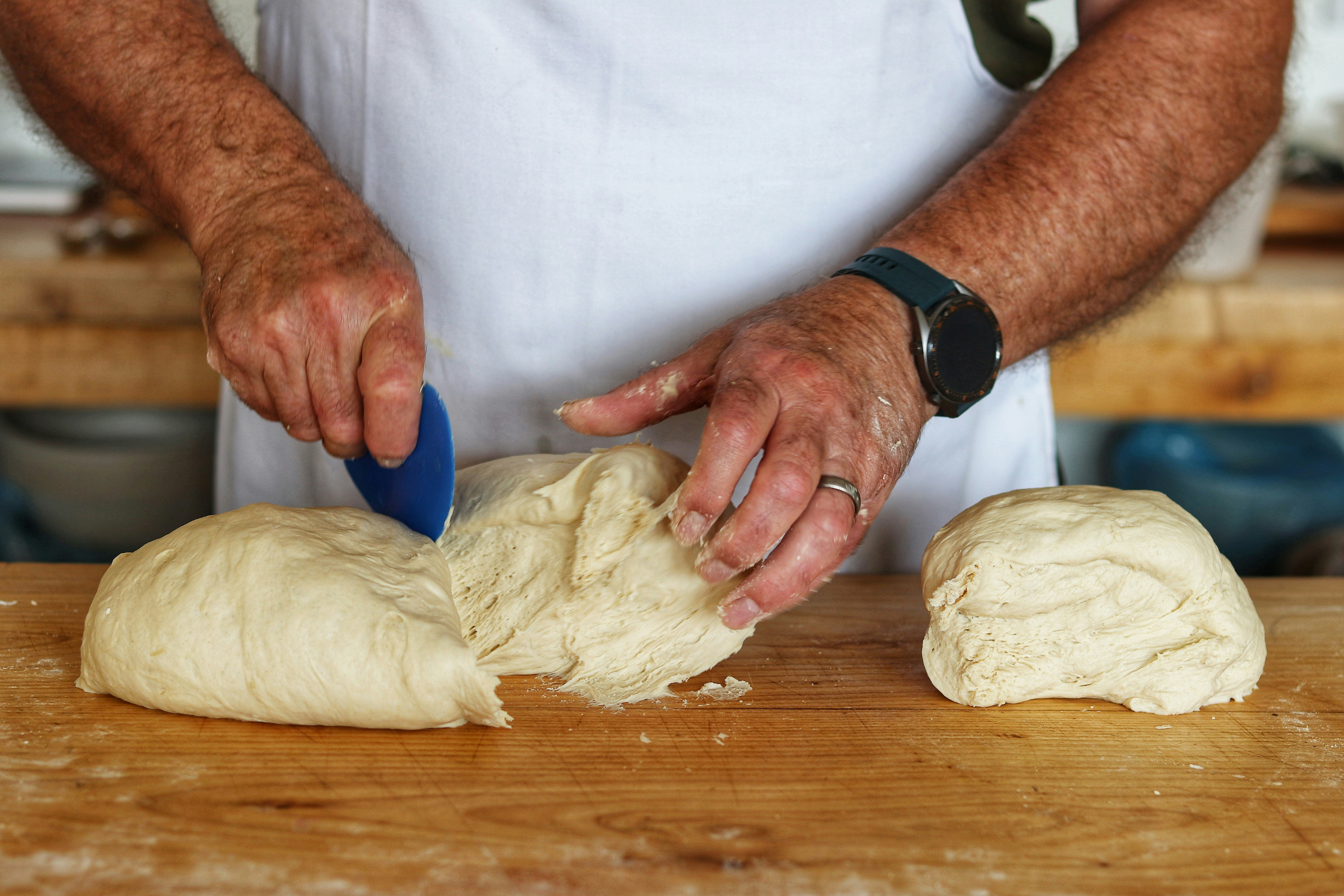 man cutting dough into 3 sections
